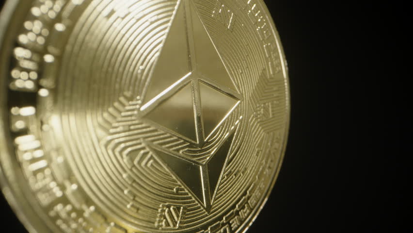 Ethereum Coin Rotating with Golden Light Reflecting Brilliantly Across Its Surface. The Iconic Logo and Detailed Engravings Stand Out Against a Black Background.