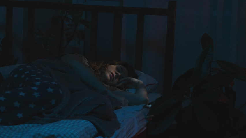 Get up for work. Alarm clock on smartphone wakes up woman at night before dawn. Early start in the morning.