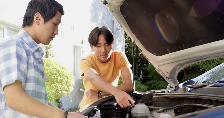 Examining car engine, asian father teaching son about vehicle maintenance outdoors. Automotive, repair, bonding, mechanic, education, family