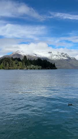 Breathtaking video of snow-capped mountains surrounding Queenstown, overlooking a stunning blue lake under a clear sky. Perfect for travel, nature, and landscape projects.