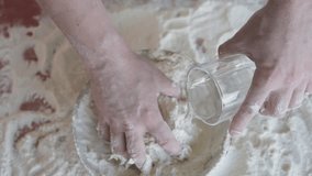 The cook pours water into flour and kneads the dough. A professional baker prepares dough for bread or dessert and pizza. Slow motion. - Powered by Shutterstock - Get 15% off with code: PIKWIZARD15