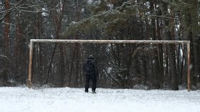 An older man is joking around while imitating a soccer game on a snowy soccer field. The man stands with his back to the soccer goal. - Powered by Shutterstock - Get 15% off with code: PIKWIZARD15