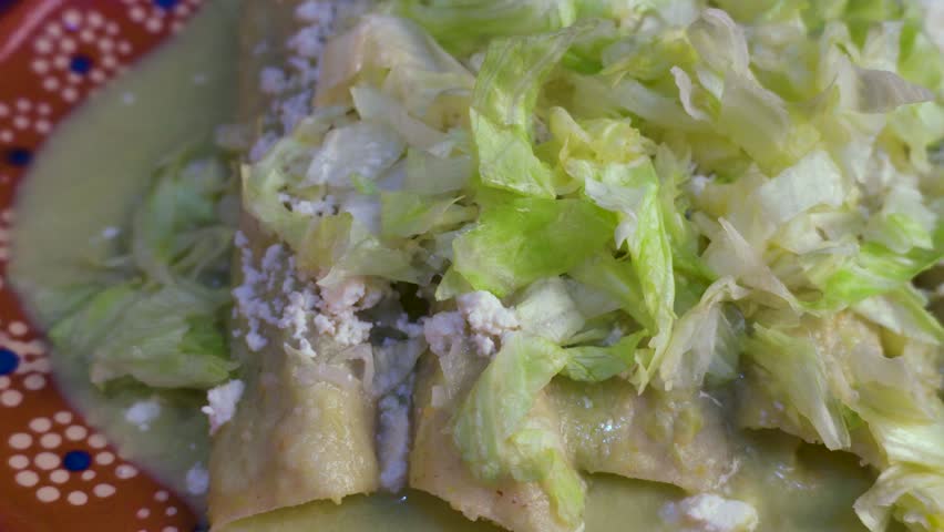 Displacement on plate with green enchiladas. Mexican food.