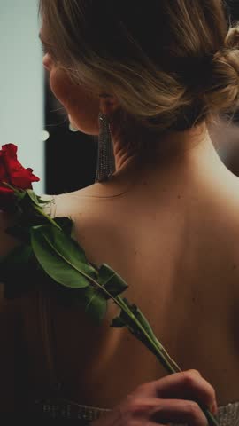 Happy Romantic couple portrait man touching stroking sexy woman back skin with red rose flower seductive body part Adult Beauty girl in shiny evening dress. window black night room vertical video crop