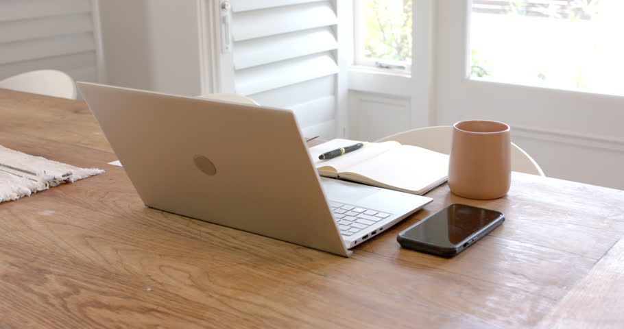 Laptop, smartphone, notebook, and coffee mug on wooden table in home office. Remote working, technology, productivity, workspace, freelance, digital nomad