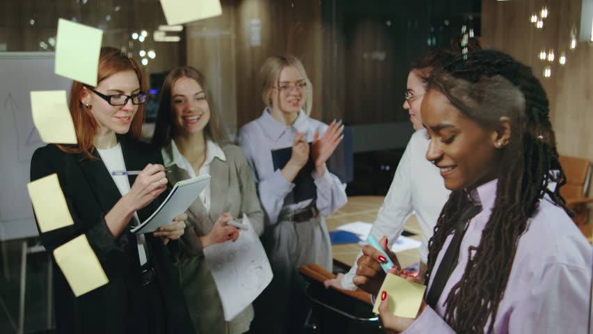 A dynamic team collaboration is taking place in a creative workspace where women are actively engaged in lively discussions and meticulous planning for their next big project
