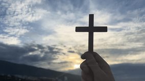 Christian prayer. Man or woman holding cross, sunset in background. Kneeling prayer to God - Powered by Shutterstock - Get 15% off with code: PIKWIZARD15