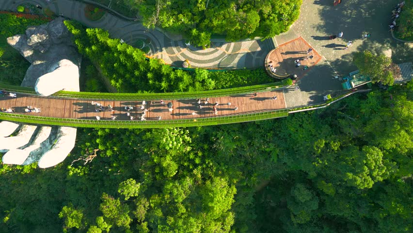 Aerial view Golden Bridge held by giant hands amidst lush greenery in Ba Na Hills, Vietnam.
