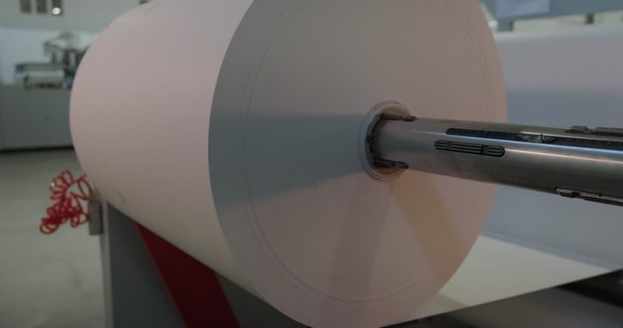 Close-up of a large industrial paper reel in a factory, showing precision in material handling and production processes