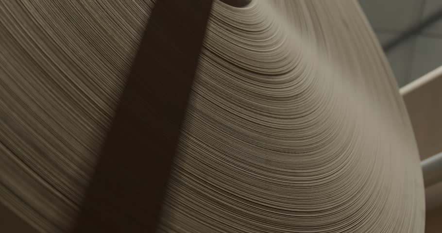 Close-up of a large industrial paper reel used in manufacturing, highlighting layered textures and production processes in a factory setting