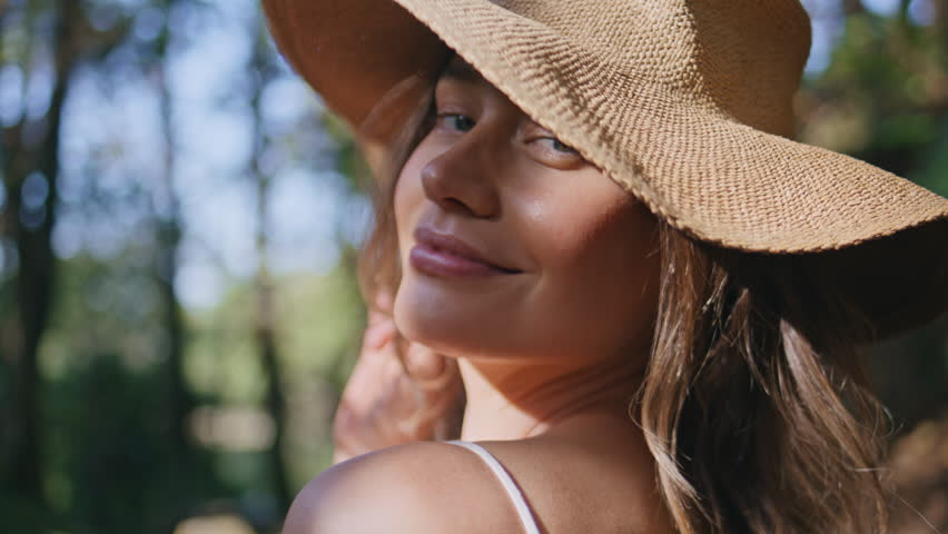 Lady shoulder fern shadow at forest closeup. Gentle smiling model girl basking in bright sun shine at greenery wild jungles. Flirting tender woman in hat standing lush plants garden resting nature