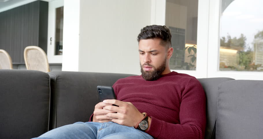 Relaxing on couch, man using smartphone and looking stressed at home. Technology, lifestyle, relaxation, device, communication, solitude
