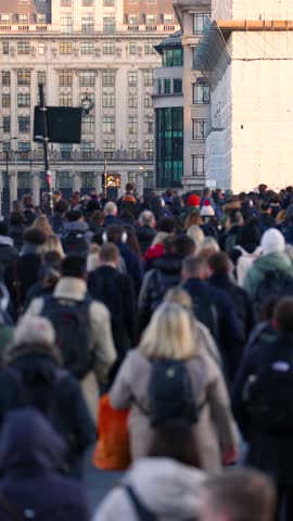 Slow motion shallow focus view of crowds of commuters on London Bridge rushing into the City offices during sunrise