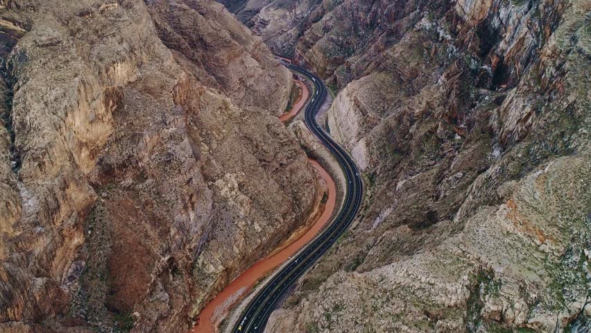 Curving highway surrounded by towering canyon walls - rugged beauty, drone view