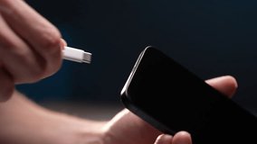 Close-up hands of unrecognizable man plugging charging cable into phone and unplugging it, repeating action multiple times standing on black background. Concept of contemporary technology convenience. - Powered by Shutterstock - Get 15% off with code: PIKWIZARD15