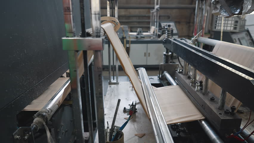 Automated machine processing the fabric used for eco bags manufacturing. Conveyor machine divides the sustainable material for eco bags. Machine producing the eco friendly bags at the facility.