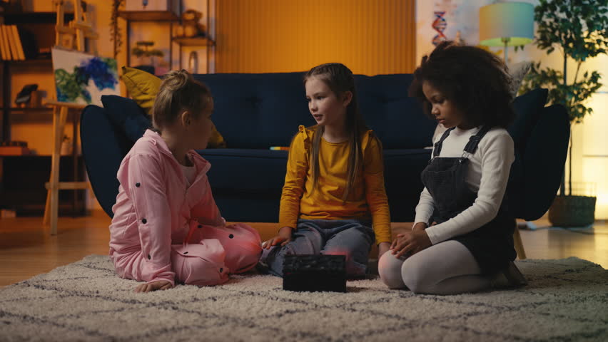 Three little girls tell spooky stories and open a mysterious box, feeling scared