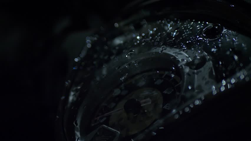 Raindrops over the speedometer of a motorcycle on a dark night.