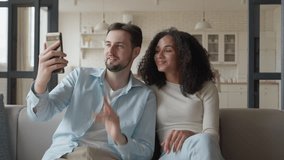 Young Smiling Couple Holding Smartphone and Making Video Call at Home - Powered by Shutterstock - Get 15% off with code: PIKWIZARD15