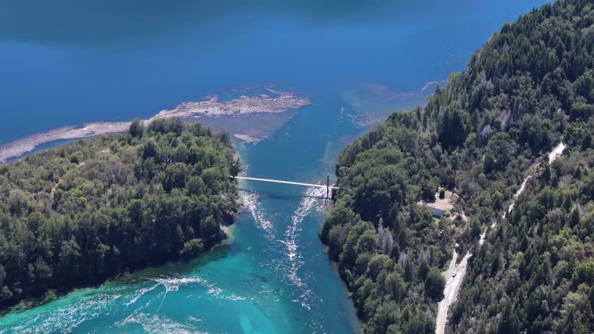 A stunning high aerial view of the suspension bridge spanning the River Arrayanes in Parque Nacional Los Alerces, Argentina, showcasing the lush landscapes and natural beauty of the region.