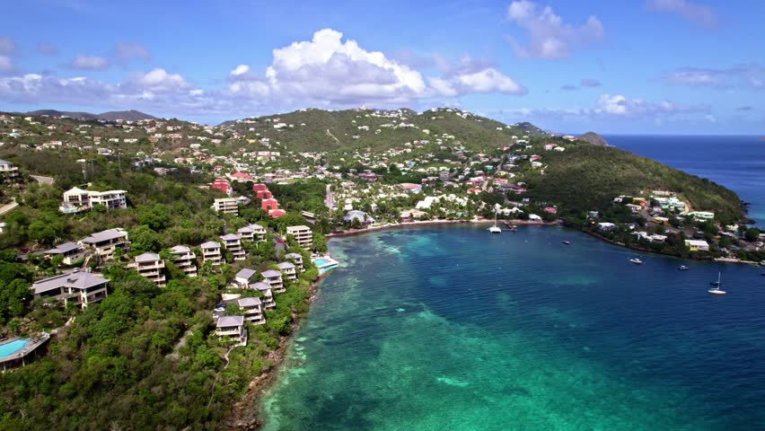 Aerial establishing orbit of bay in St. Thomas, USVI, scenic coastal views with lush vegetation and turquoise seas luxury homes and villas looking to water