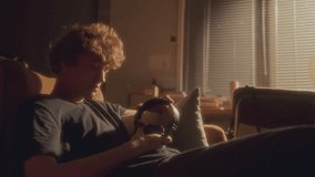 Young depressed man sitting on couch, putting headphones on, listening to music with eyes closed in living room filled with soft sunlight - Powered by Shutterstock - Get 15% off with code: PIKWIZARD15