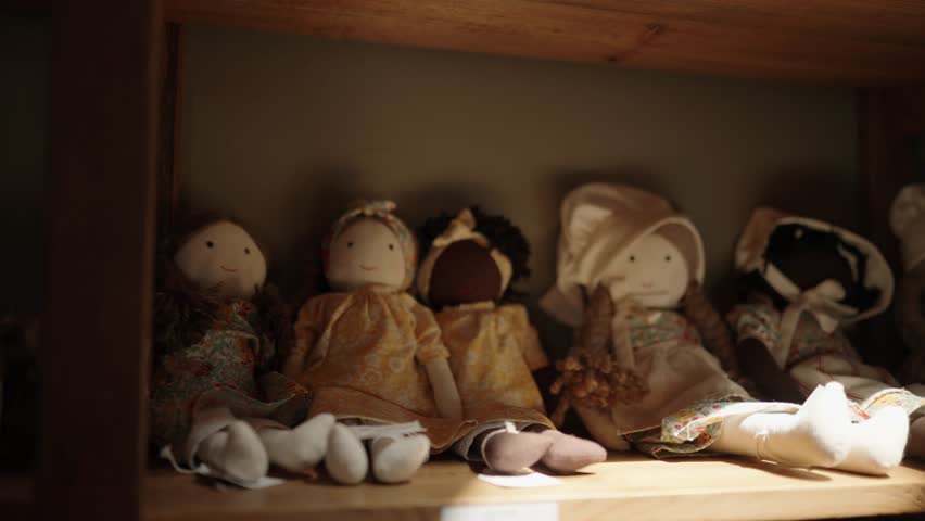 Collection of beautiful old soft dolls sitting on a shelf dressed in vintage clothing
