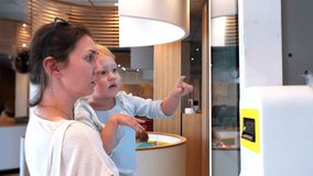 A mother and her young daughter explore a digital touchscreen menu at a modern cafe. They interact with the display selecting their meal together enjoying a family moment with innovative technology. - Powered by Shutterstock - Get 15% off with code: PIKWIZARD15