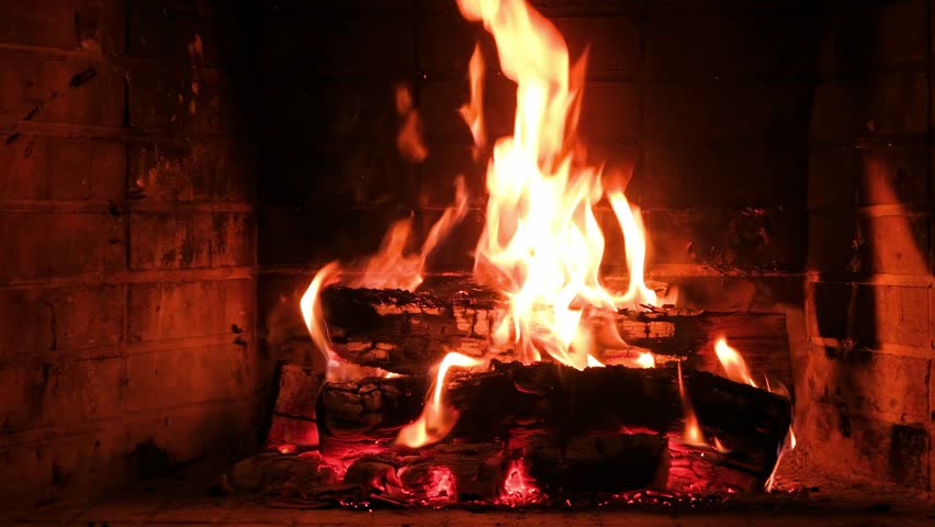 Fire burning in a fireplace, wood logs and bright flames. Warm home, heat. Christmas holiday