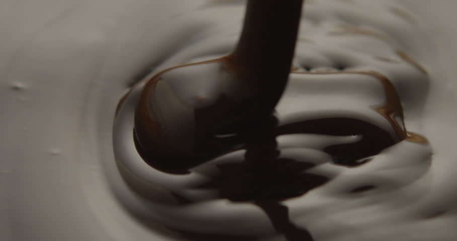 A closeup slow-motion of black honey falling into Tahini, showcasing the fluid texture and the mixing process