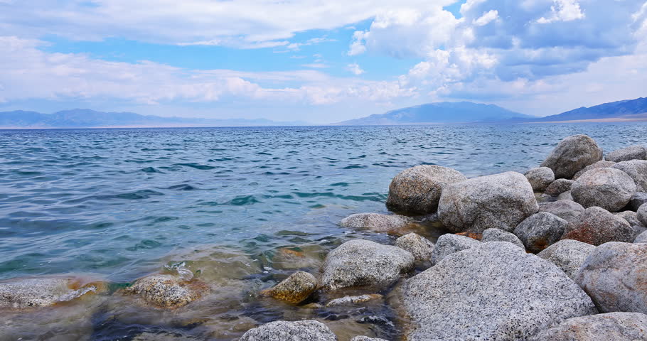Clean lake water and rock scenery under blue sky. Beautiful Sayram Lake natural landscape in Xinjiang, China.