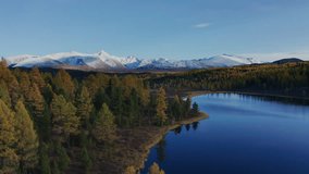 Pan left experience a stunning aerial view of Mountain Altai captured by a drone during late autumn, showcasing vibrant foliage and snow-capped peaks mirrored in a serene lake. - Powered by Shutterstock - Get 15% off with code: PIKWIZARD15