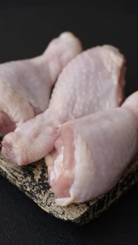 Raw chicken legs with salt, spices and herbs on a dark concrete background. Cooking lunch at home
