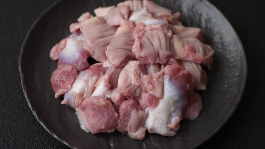 Raw chicken or turkey stomach with salt, spices and herbs on a textured concrete background
