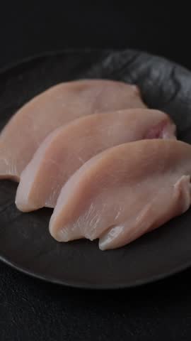 Fresh chicken fillet on a dark concrete table with spices and herbs. Preparation for cooking meat dishes