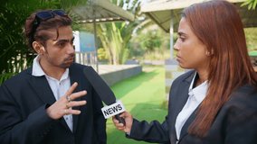 Lady journalist standing anchoring businessman in park, Female reporter stands conducting live interview outdoor, Newswoman holding a microphone questioning man, For the press, Girl interrogating Boy - Powered by Shutterstock - Get 15% off with code: PIKWIZARD15