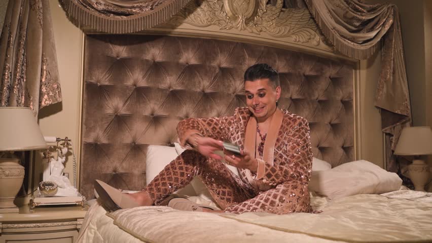 Rich and eccentric man wearing golden suit with a lot of US dollar bills in a luxurious suite