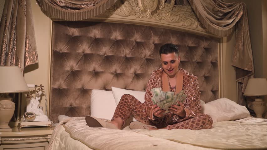 Rich and eccentric man wearing golden suit with a lot of US dollar bills in a luxurious suite