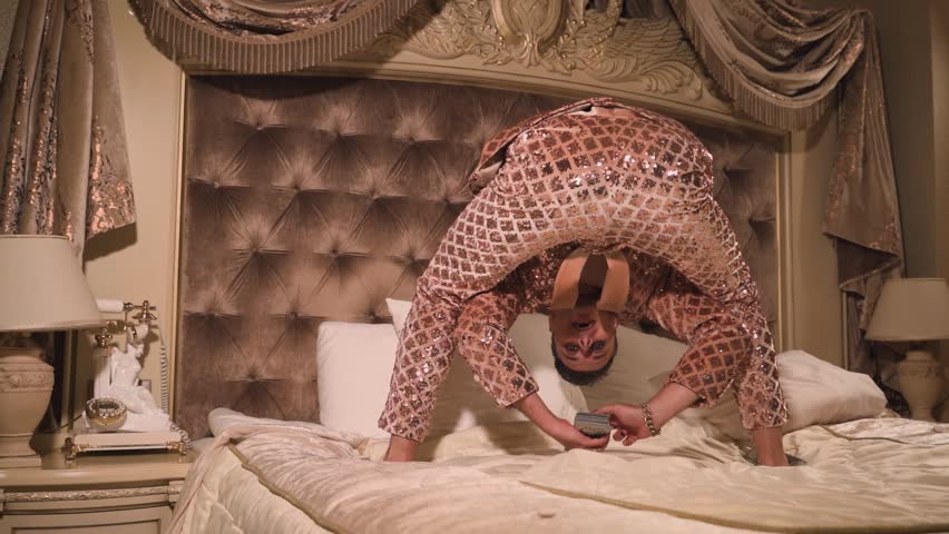 Rich and eccentric man wearing golden suit with a lot of US dollar bills in a luxurious suite