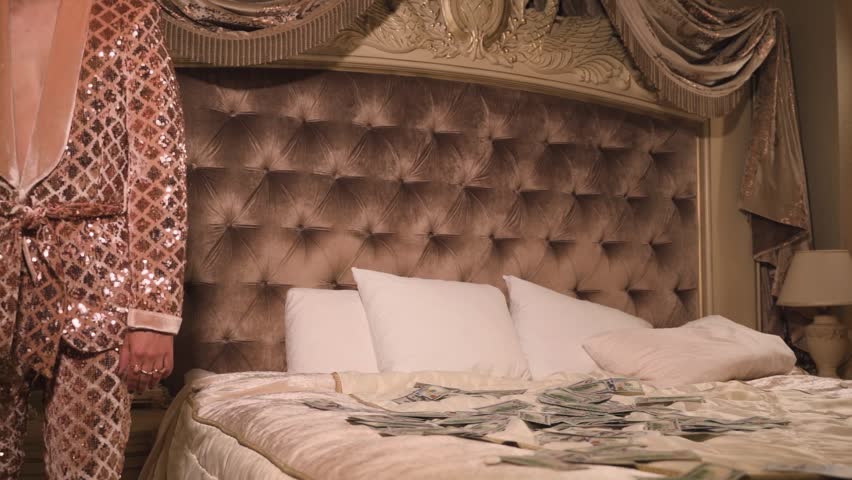 Rich and eccentric man wearing golden suit with a lot of US dollar bills in a luxurious suite