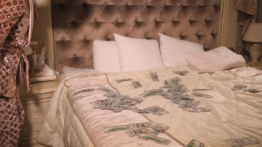 Rich and eccentric man wearing golden suit with a lot of US dollar bills in a luxurious suite