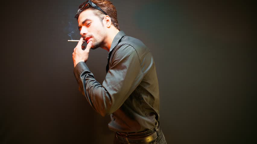 Man stands confidently while modeling with cigarette, Model standing strikes a pose as enjoying his smoke, Guy shows stance for photo collection, Captures cool style, Male looks great in the portfolio