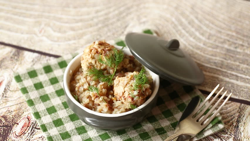 cooked boiled buckwheat with chicken meatballs in ceramic bowl on wooden table