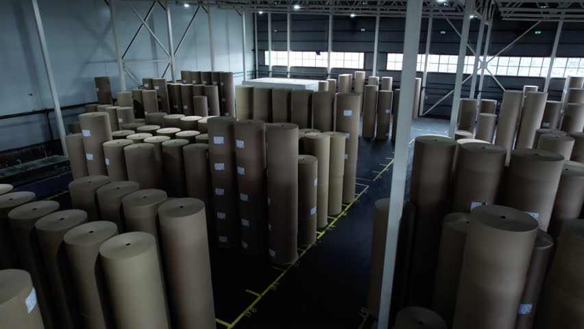 Hall of cardboard factory containing products with labelling. Warehouse stores tall rolls for distribution of material to receiving points