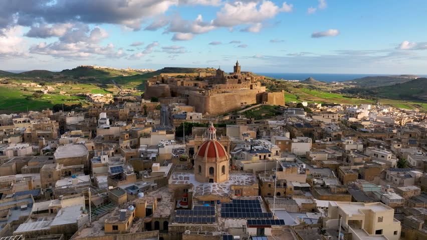 4k Aerial view of Historic fort, Citadel Ruins on cliff overlooking valley at sunset with lush greenery in the background. island Gozo. Malta