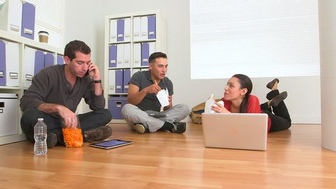 Mexican and Caucasian employees eating food on floor of office