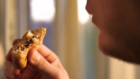  A young man eats a croissant with chocolate, slow motion. Portrait of a man with pastries in his hands - Powered by Shutterstock - Get 15% off with code: PIKWIZARD15