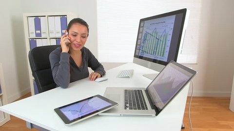 Hispanic business woman working on laptop and phone