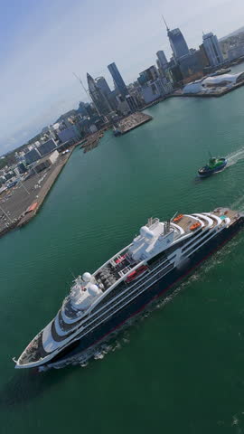 Aerial view of a luxury yacht departing Auckland Harbour, New Zealand, with stunning city skyline and serene waters.