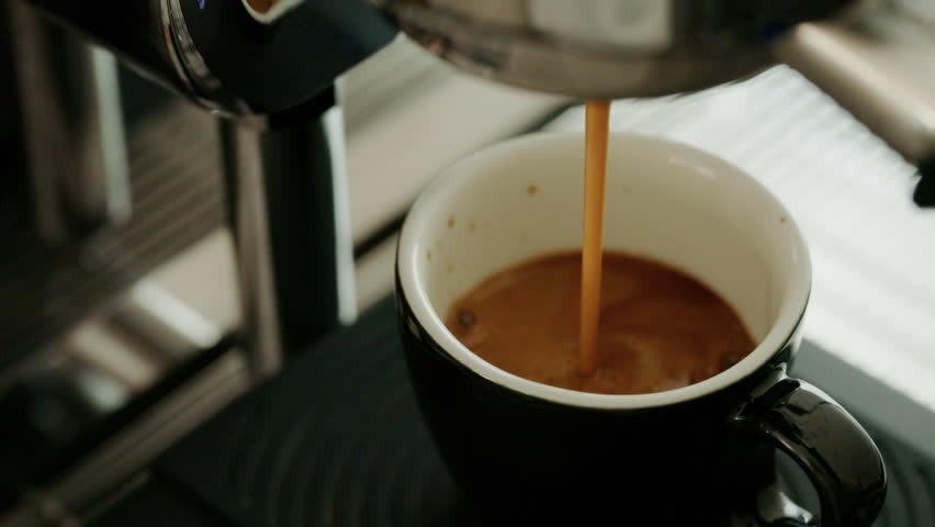 4K Espresso pouring from coffee machine at cafe,Brewing the espresso coffee from the machine warm tone